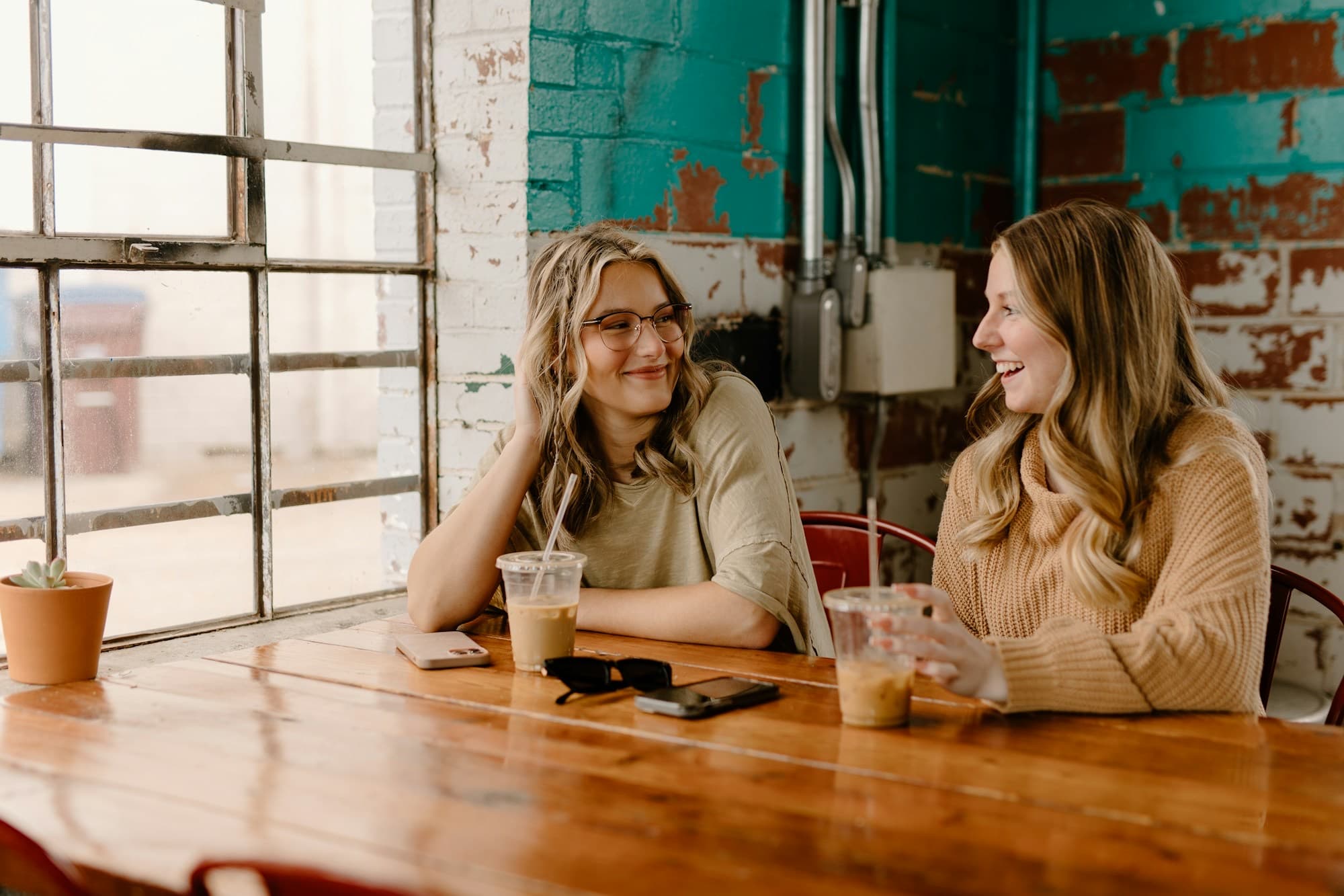 Two women laughing together over coffee